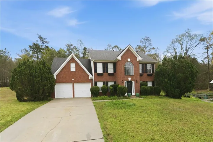 Brick facade residence with a two-car garage, mature landscaping, and an arched entry window