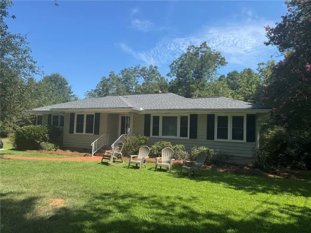 Charming single-story residence with a classic exterior featuring multiple large windows and a welcoming front porch with railings