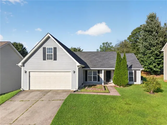 Light grey siding with a two-car garage, a dark grey shingle roof, and a mature front lawn