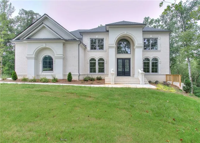View of front of property featuring brick siding, a front yard, french doors, and roof with shingles