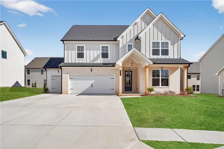 Modern inspired farmhouse with board and batten siding, a front yard, brick siding, concrete driveway, and a garage