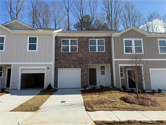 Contemporary townhome exteriors featuring brick and siding facades, individual garage entrances, and established landscaping elements