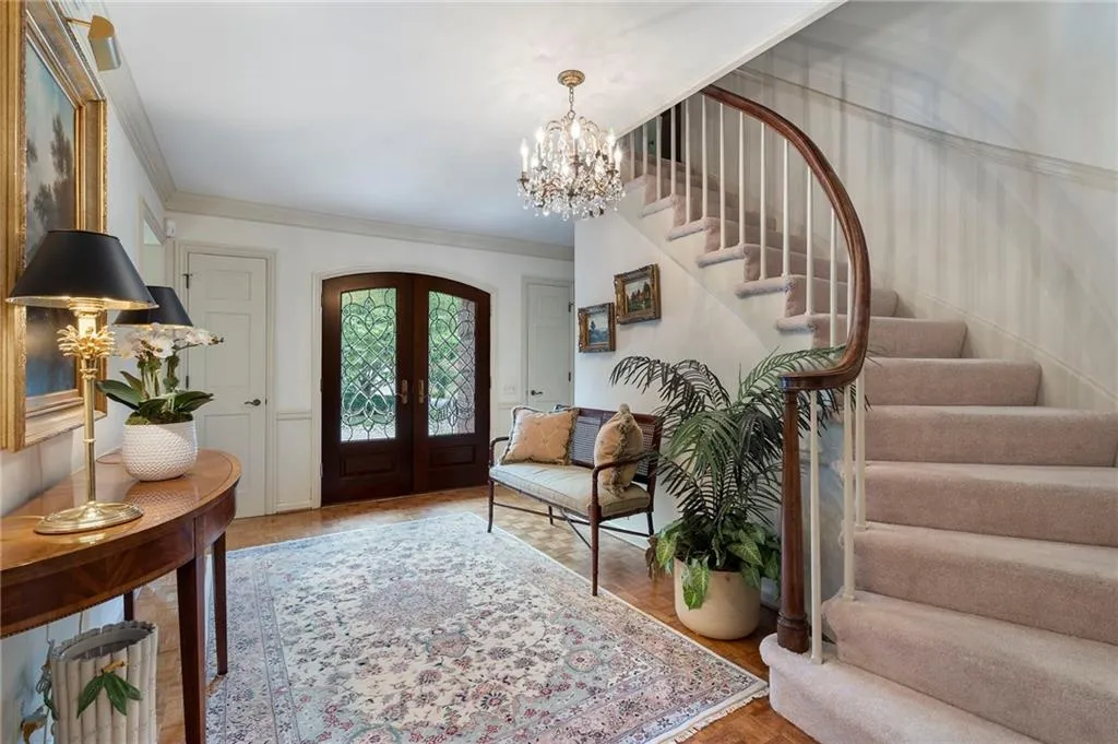 Custom front doors and sweeping staircase leading to the upper level