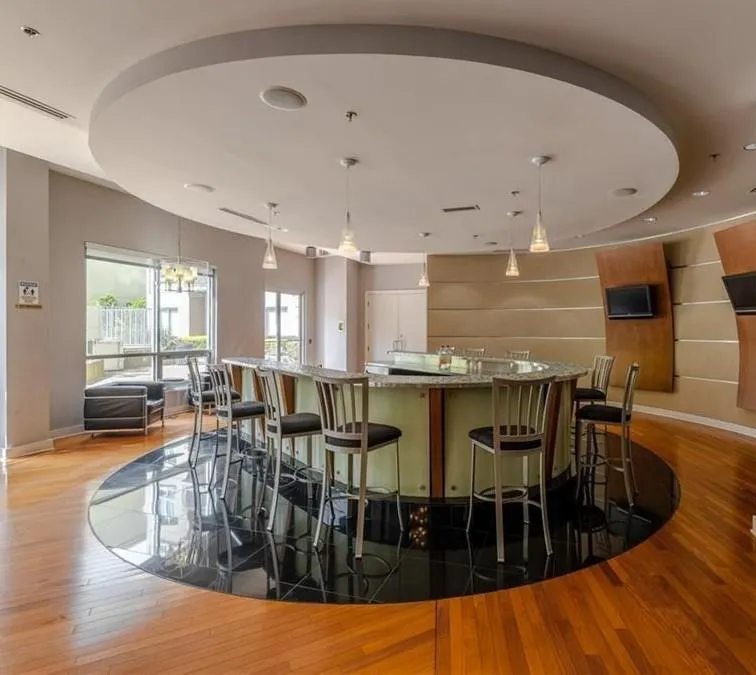 Bar featuring light wood finished floors, hanging light fixtures, and recessed lighting