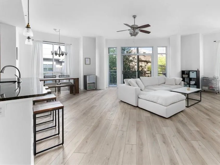 Living area with light wood finished floors, a ceiling fan, plenty of natural light, and a chandelier