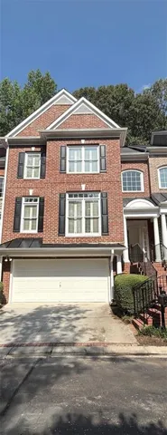 Brick townhouse with black shutters, a two-car garage, and a covered entry