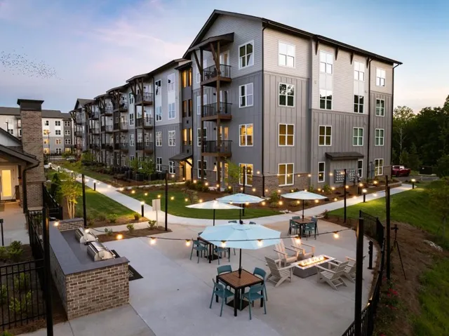 Multi-level residential building featuring private balconies, extensive hardscaping, built-in outdoor grilling station, and a fire pit area