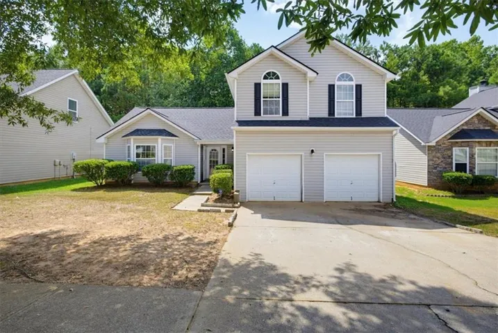 Two-story residence featuring light-colored siding, a dual-car garage, and a bay window