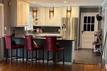 Kitchen with hanging light fixtures, porcelain flooring, a peninsula, stainless steel refrigerator with ice dispenser, and a kitchen breakfast bar