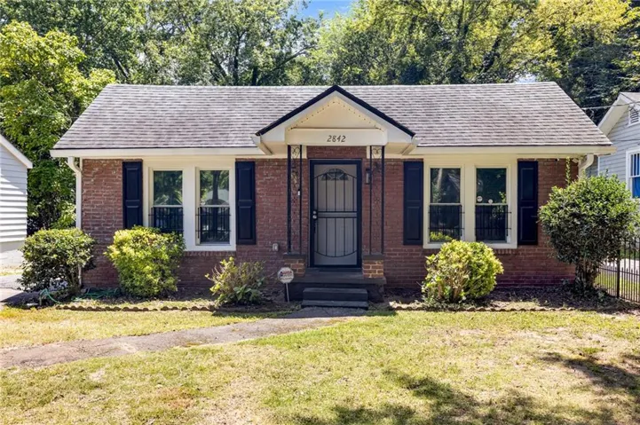 Brick facade with dark shutters and a covered entry
