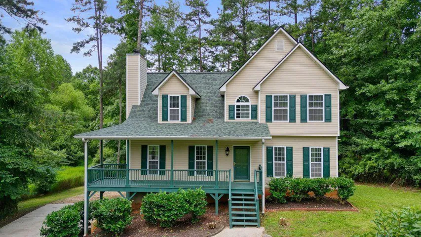 Two-story residence featuring light-colored siding and a dark green shingle roof