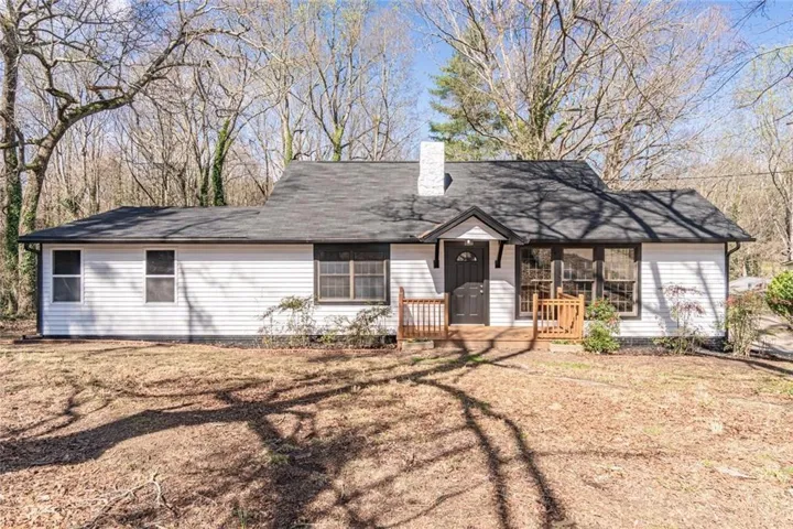 View of front of home featuring a chimney and a porch
