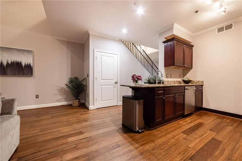 Kitchen with crown molding, stainless steel dishwasher, a peninsula, dark wood-style floors, and dark brown cabinets