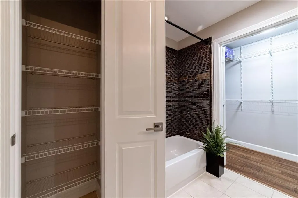 Bathroom with tile patterned flooring, tub / shower combination, and a spacious closet