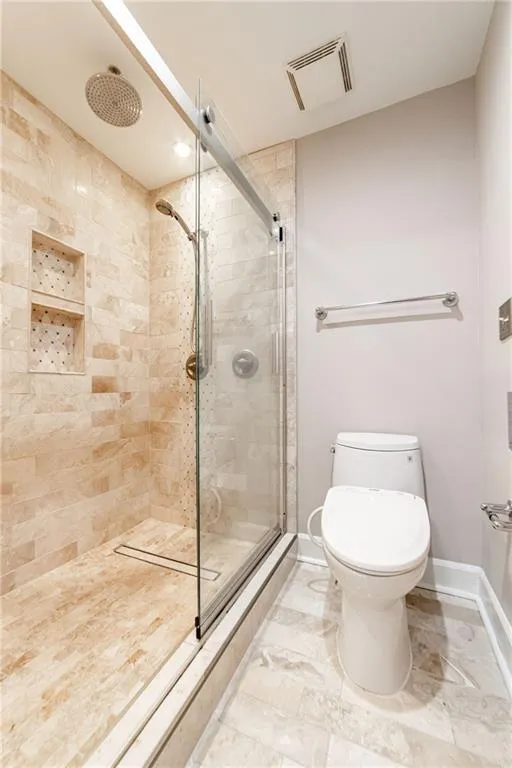 Bathroom featuring a tile shower and marble finish floors