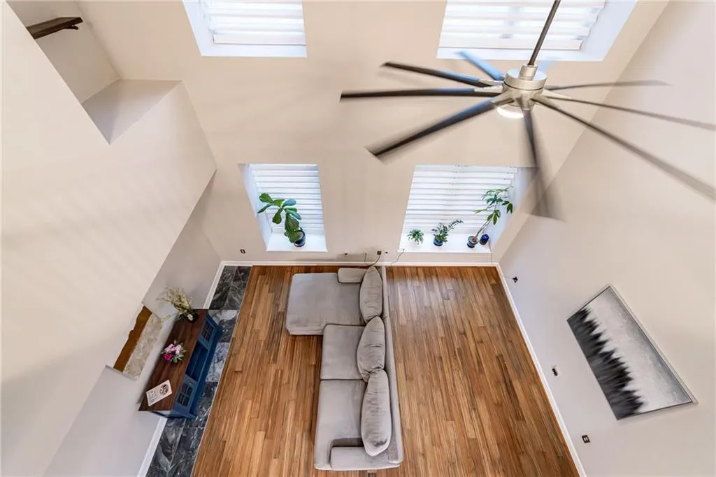 Living room featuring a ceiling fan, wood finished floors, and a high ceiling