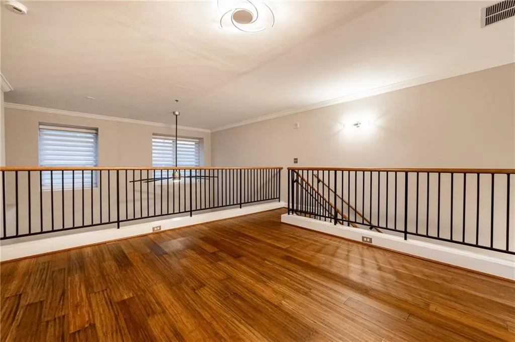 Spare room featuring wood finished floors, ornamental molding, and a smoke detector