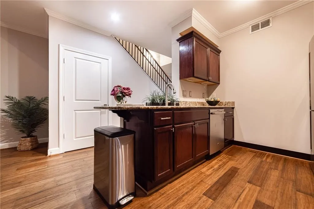 Bar area with light wood-type flooring, stainless steel dishwasher, and crown molding