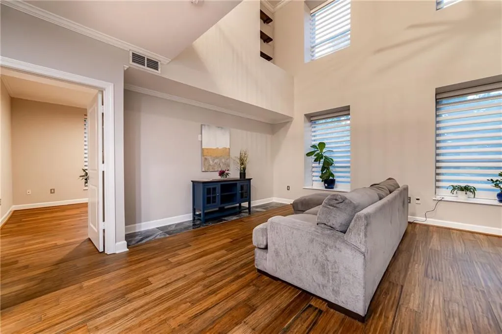 Living room with wood finished floors, ornamental molding, and a high ceiling