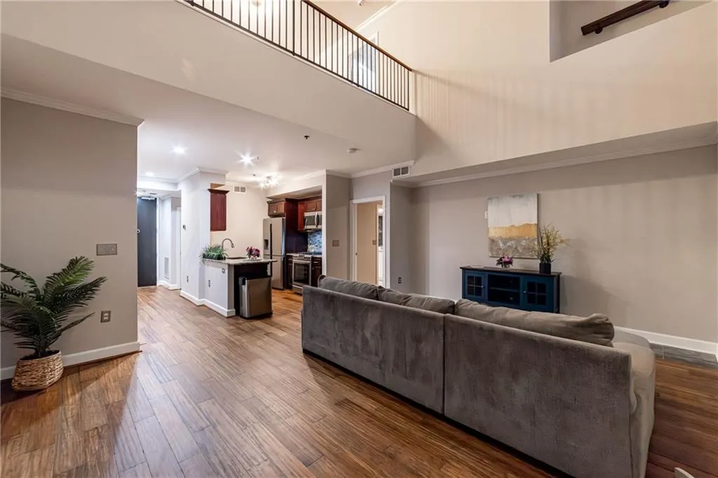 Living area with crown molding, wood finished floors, recessed lighting, and a high ceiling