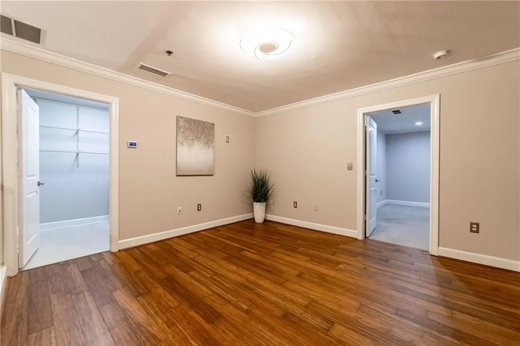 Spare room with wood finished floors, ornamental molding, and a smoke detector