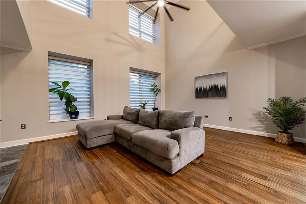 Living room with dark wood-type flooring, a high ceiling, and ceiling fan