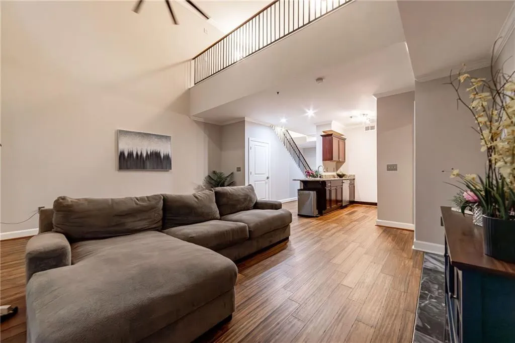 Living room featuring crown molding, light wood-type flooring, and a high ceiling