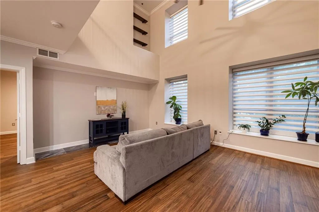 Living area with crown molding, dark wood-type flooring, and a high ceiling