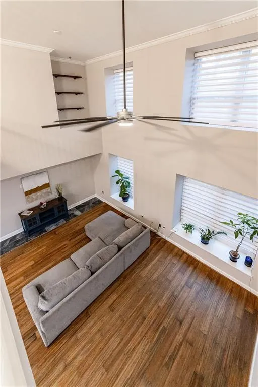 Living room featuring wood finished floors, ornamental molding, plenty of natural light, and a ceiling fan