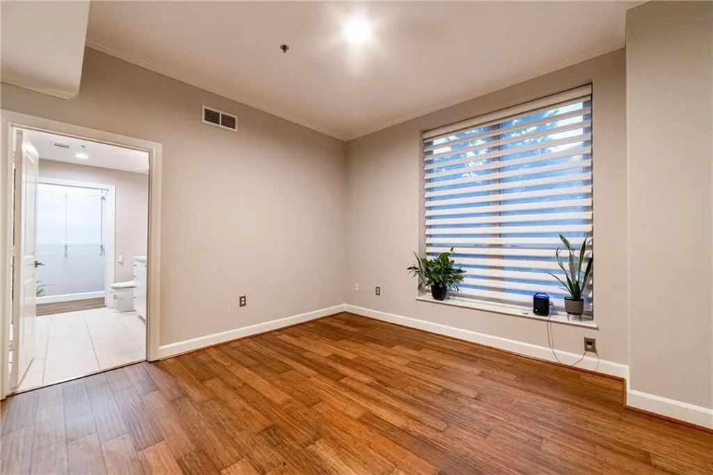Empty room featuring ornamental molding and wood finished floors