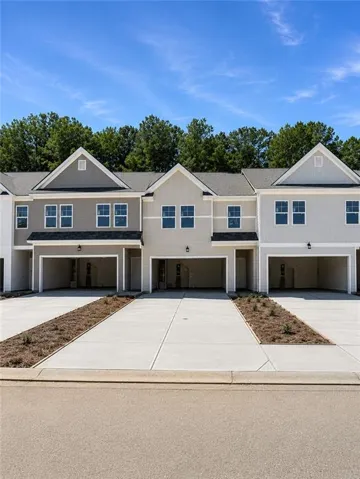 Contemporary townhome exteriors with varied siding textures, individual paved driveways, attached garage spaces, and gabled rooflines