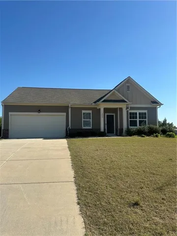 View of front facade featuring driveway, a front yard, board and batten siding, and a garage
