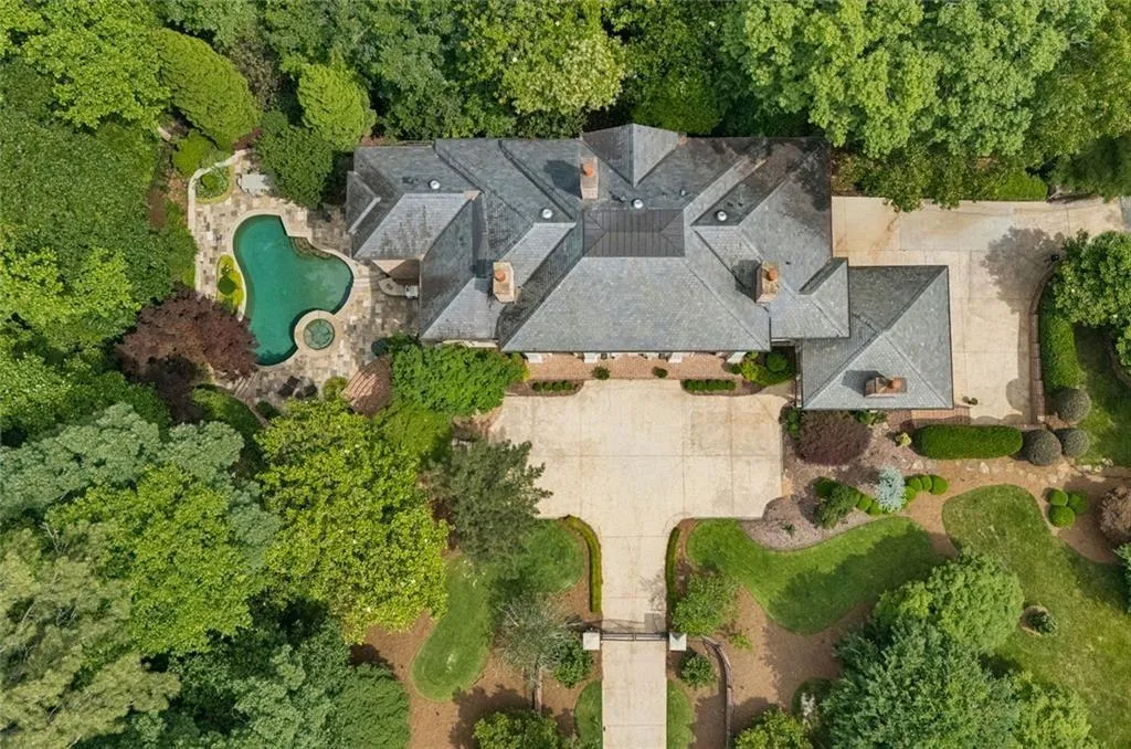 Slate roof, sweeping motor court, gated entry, lush manicured grounds, and a private pool tucked among the treetops.