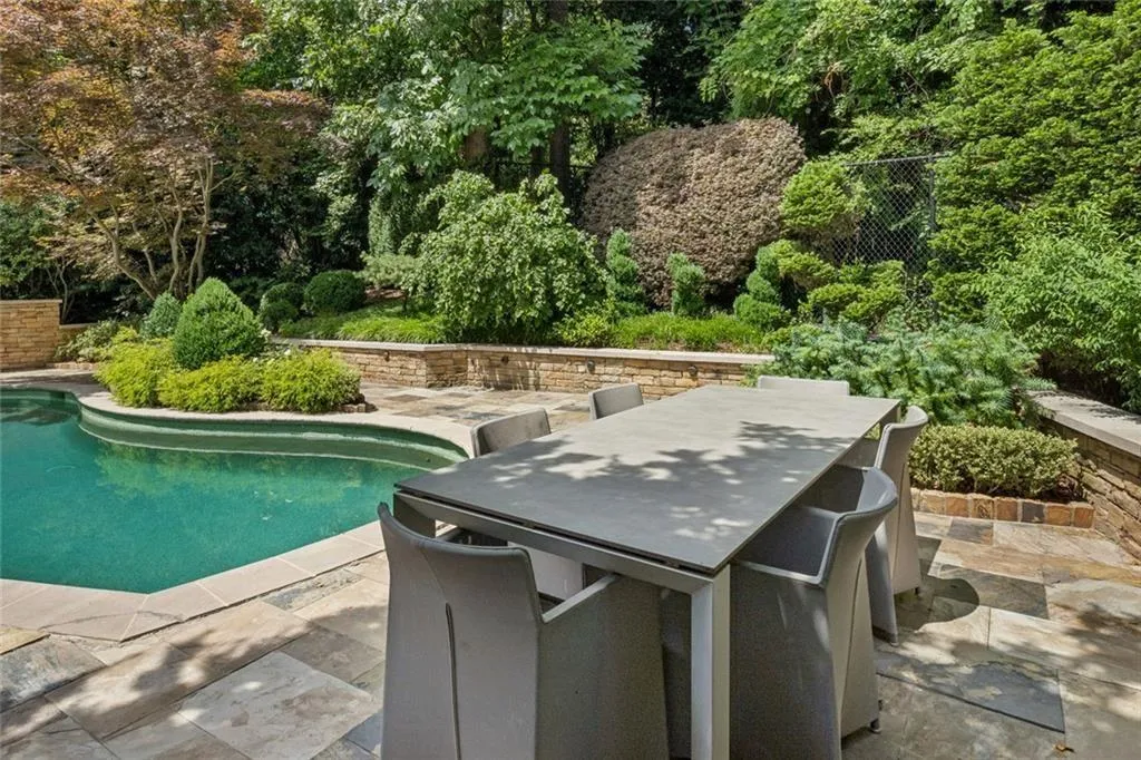 Al fresco dining poolside, surrounded by lush mature landscaping and manicured gardens.
