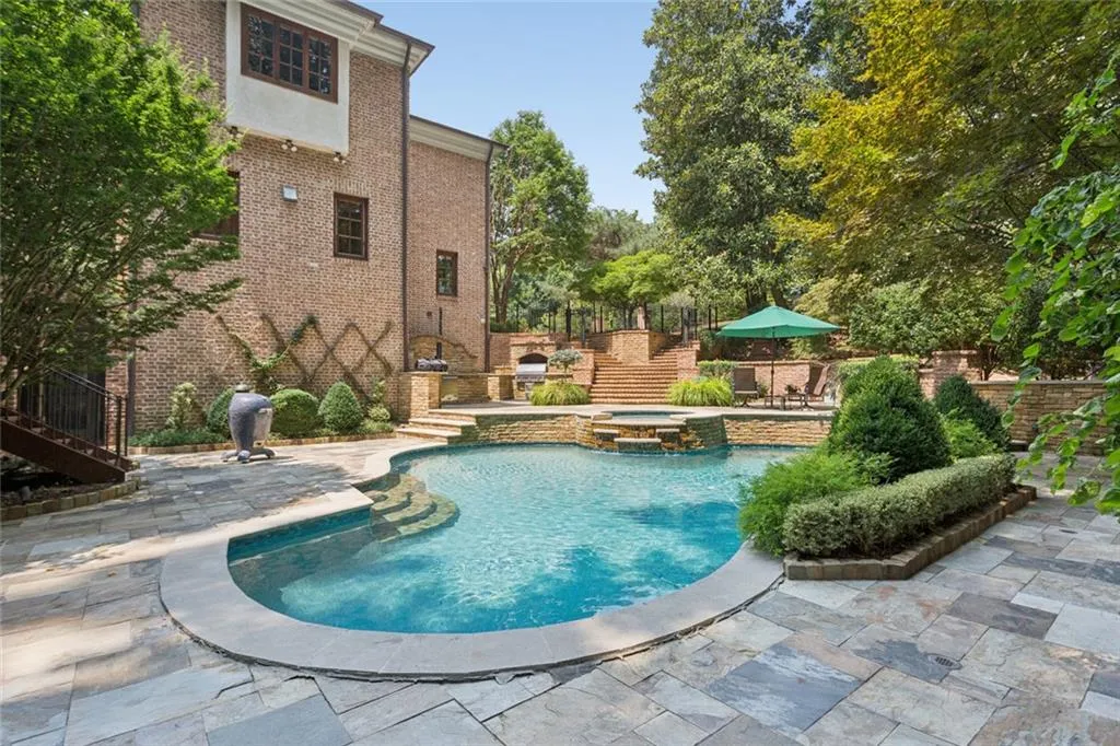 Slate roof, sweeping motor court, gated entry, lush manicured grounds, and a private pool tucked among the treetops.