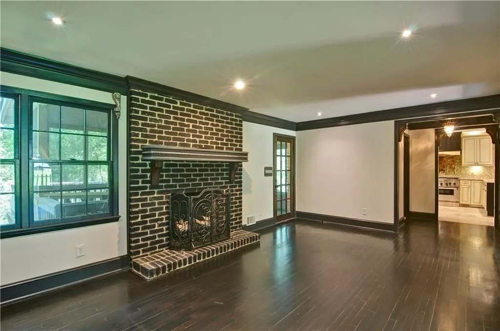 Family room featuring crown molding, brick fireplace, hardwood floors, and recessed lighting