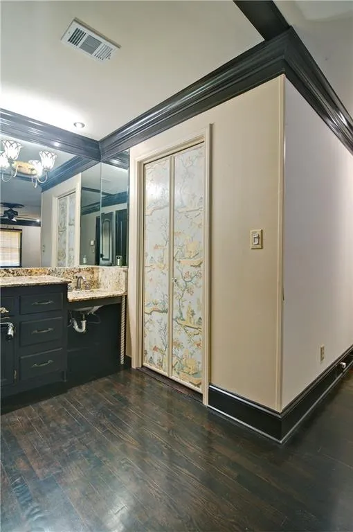 Bathroom with crown molding, granite vanity, and hardwood floors