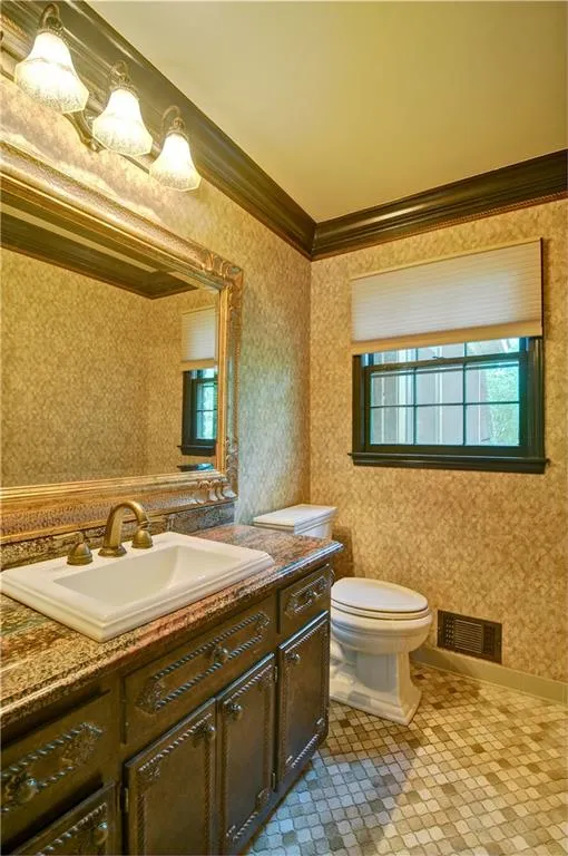 The main floor half bath offers crown molding, granite counter top and gorgeous cabinetry