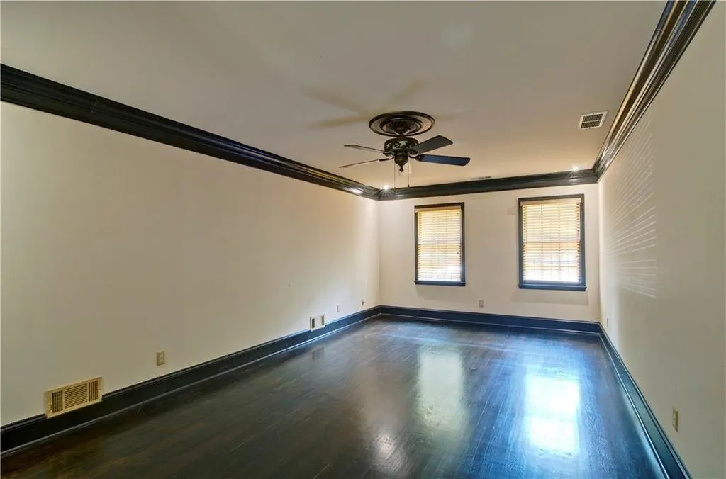 Huge primary bedroom offers crown molding and hardwood floors