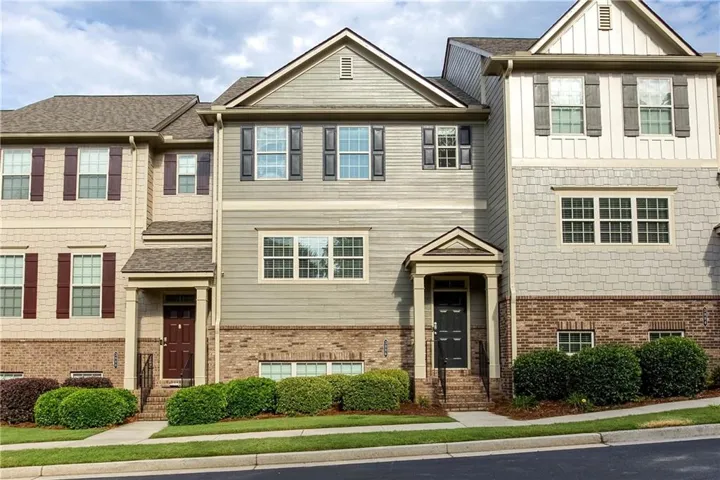Multi-level townhome featuring a varied facade with brick, horizontal siding, and shingle siding