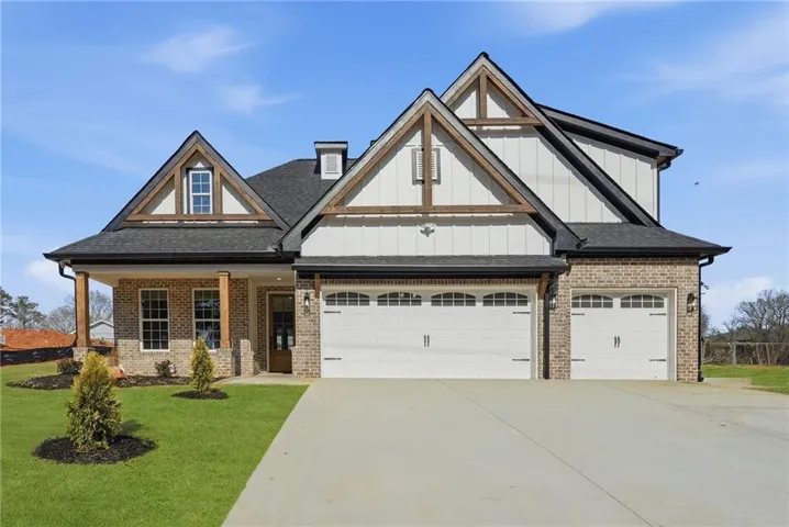 Craftsman-style home with brick siding, concrete driveway, a front yard, board and batten siding, and a porch