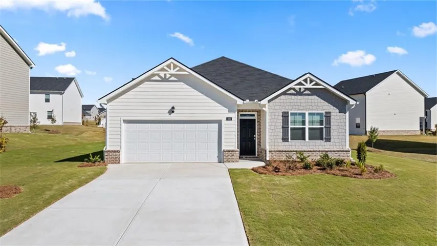 Craftsman-style home featuring brick siding, a front lawn, an attached garage, and driveway