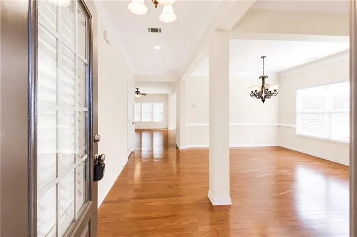 Wood-finish flooring, recessed lighting, crown molding, a decorative chandelier, and multiple windows with blinds