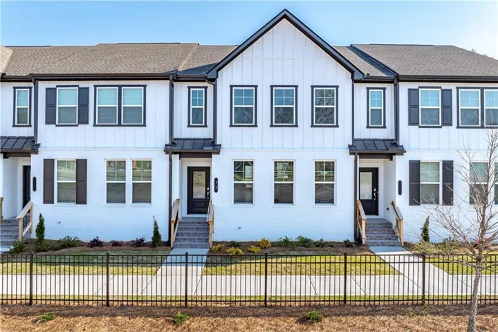 Contemporary townhome exterior featuring white brick and vertical siding with contrasting dark trim and shutters