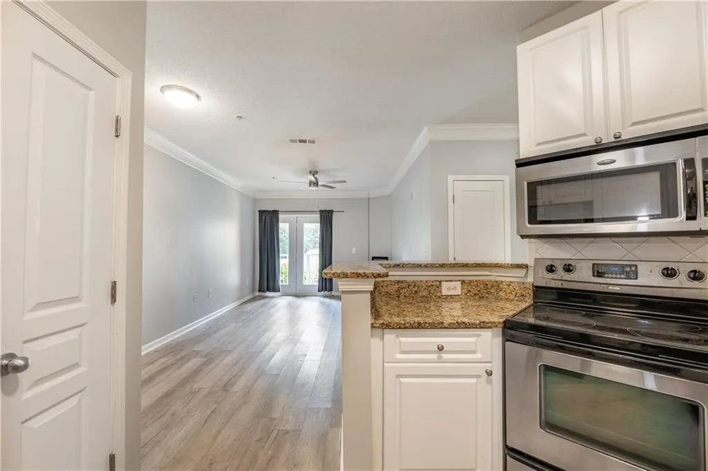 Kitchen with appliances with stainless steel finishes, ornamental molding, tasteful backsplash, white cabinets, and a peninsula