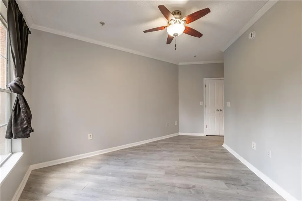 Spare room with ceiling fan, light wood finished floors, crown molding, and a smoke detector