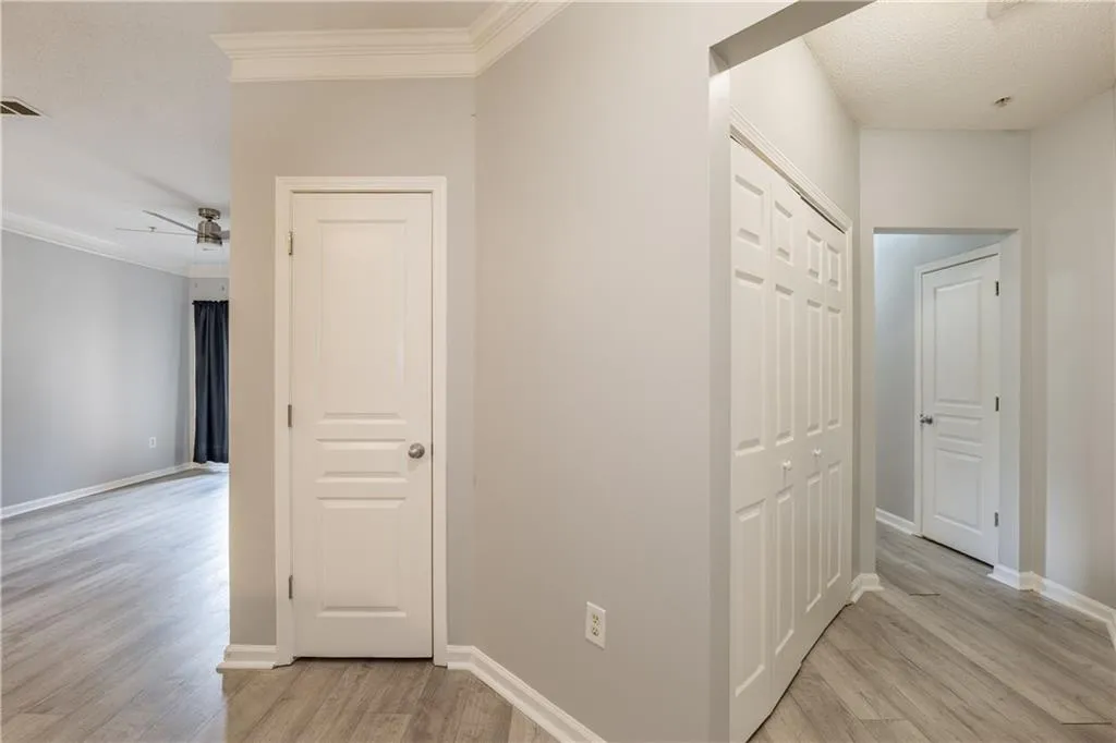 Corridor with light wood-type flooring, crown molding, and a textured ceiling