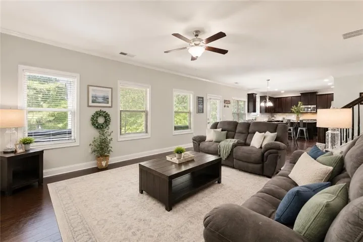 VIRTUALLY STAGED: Light-filled family room featuring expansive windows, rich hardwood floors, and an open-concept design that seamlessly connects the living, dining, and kitchen areas—creating the perfect space for everyday living and effortless entertaining.