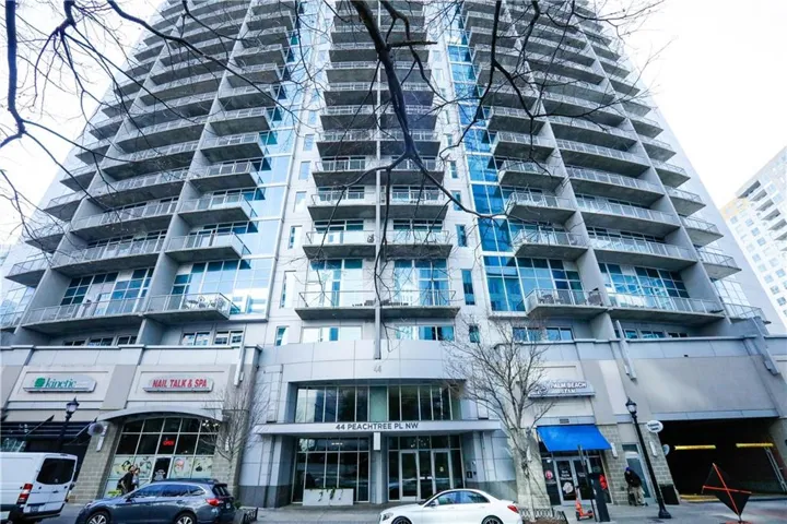 Modern high-rise building with a multi-story glass facade and private balconies on every residential level
