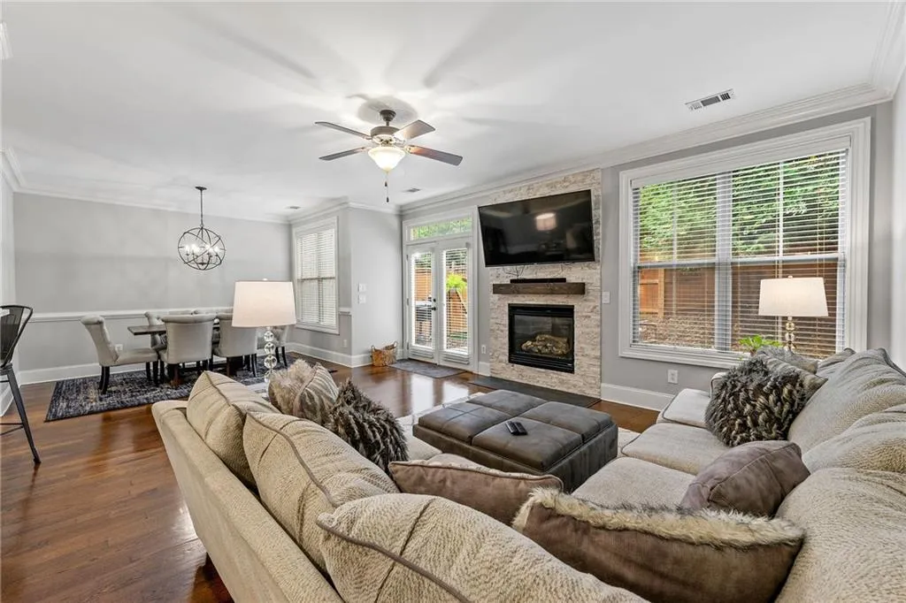 Living room with ceiling fan with notable chandelier, dark hardwood / wood-style floors, a fireplace, and crown molding